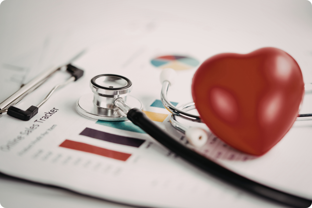 Estetoscópio médico e um coração estilizado repousando sobre relatórios de saúde e gráficos de análise diagnóstica.